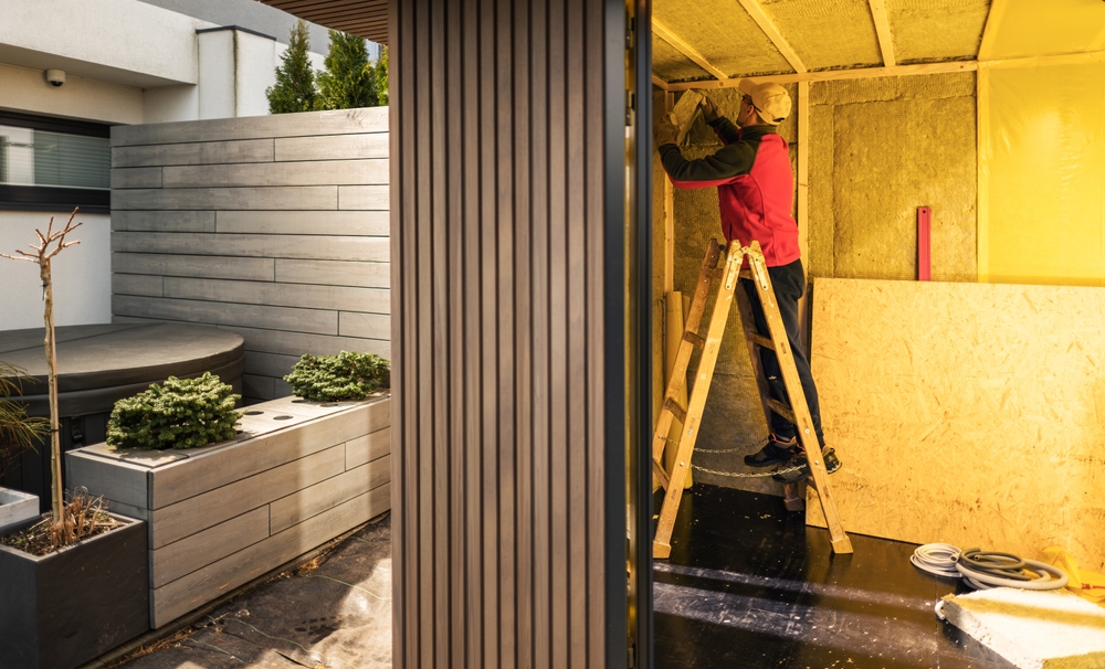 a man in a red jacket on a ladder installing insulation in a shed a man in a red jacket on a ladder installing insulation in a shed