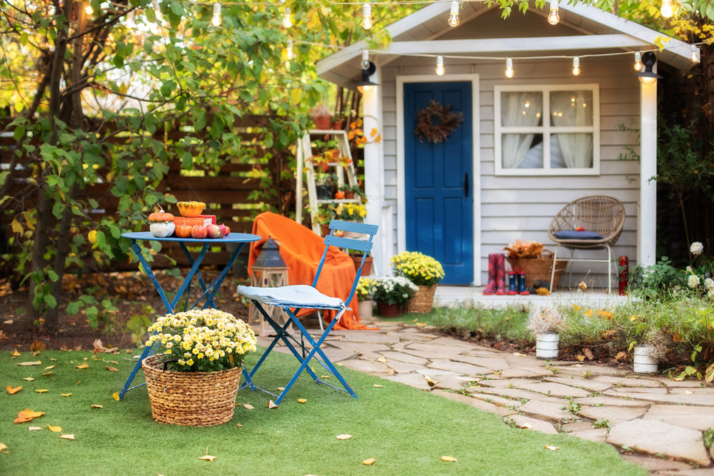 A white shed with a blue door in a large garden A white shed with a blue door in a large garden